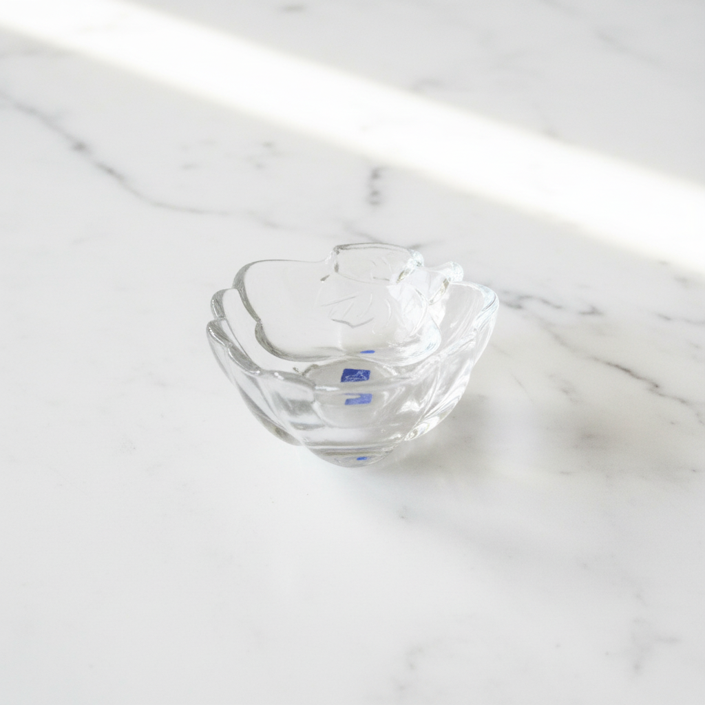 Clear glass flower dish on white marble background