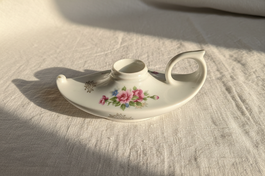 Vintage porcelain chamberstick candle holder on white linen background