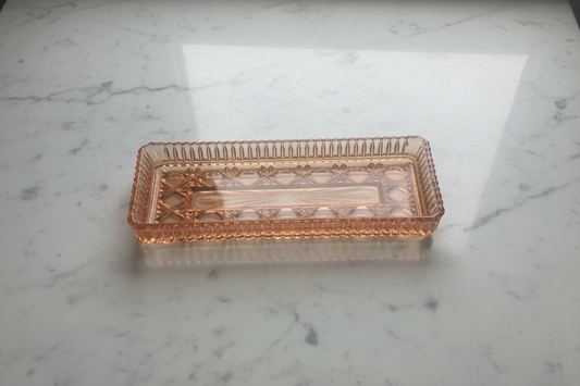 Pink depression glass tray on white marble background