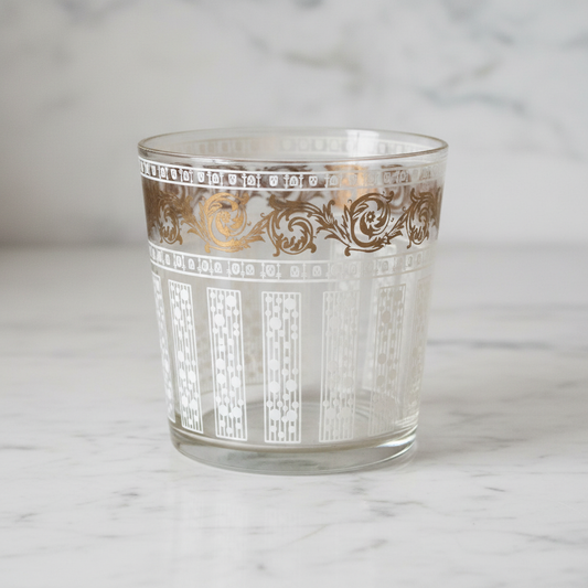 Vintage glass ice bucket with gold and white enamel decoration on white marble background